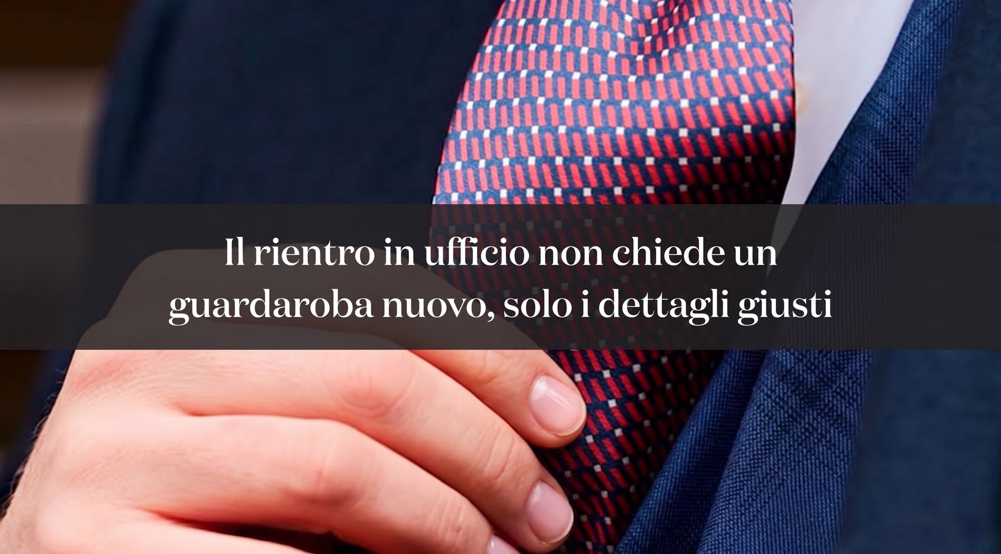 Primo piano di una mano che sistema una cravatta rossa e blu su abito blu, con titolo in sovrimpressione sul rientro in ufficio.