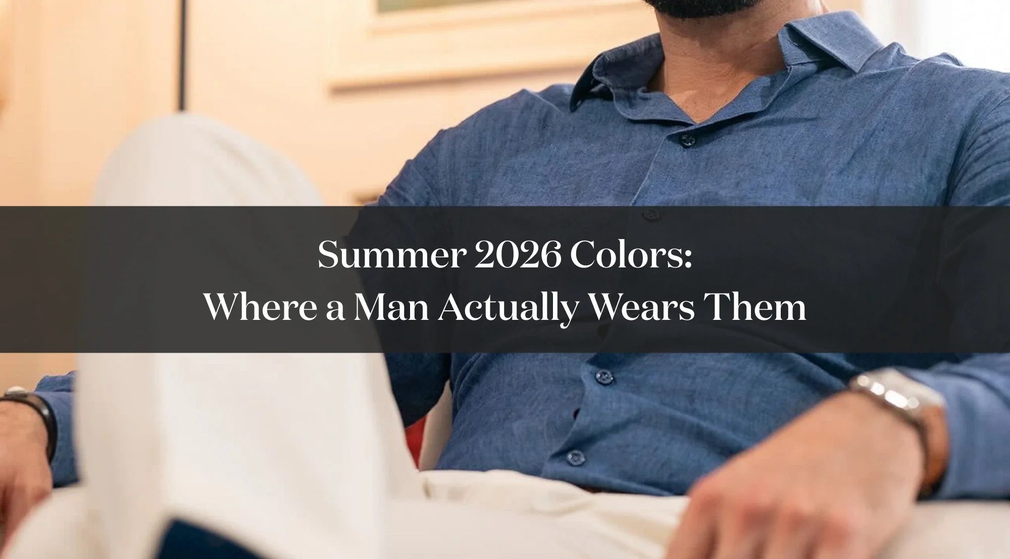 Man wearing a light blue shirt and light-colored trousers, with text about summer 2026 colors in men’s fashion.
