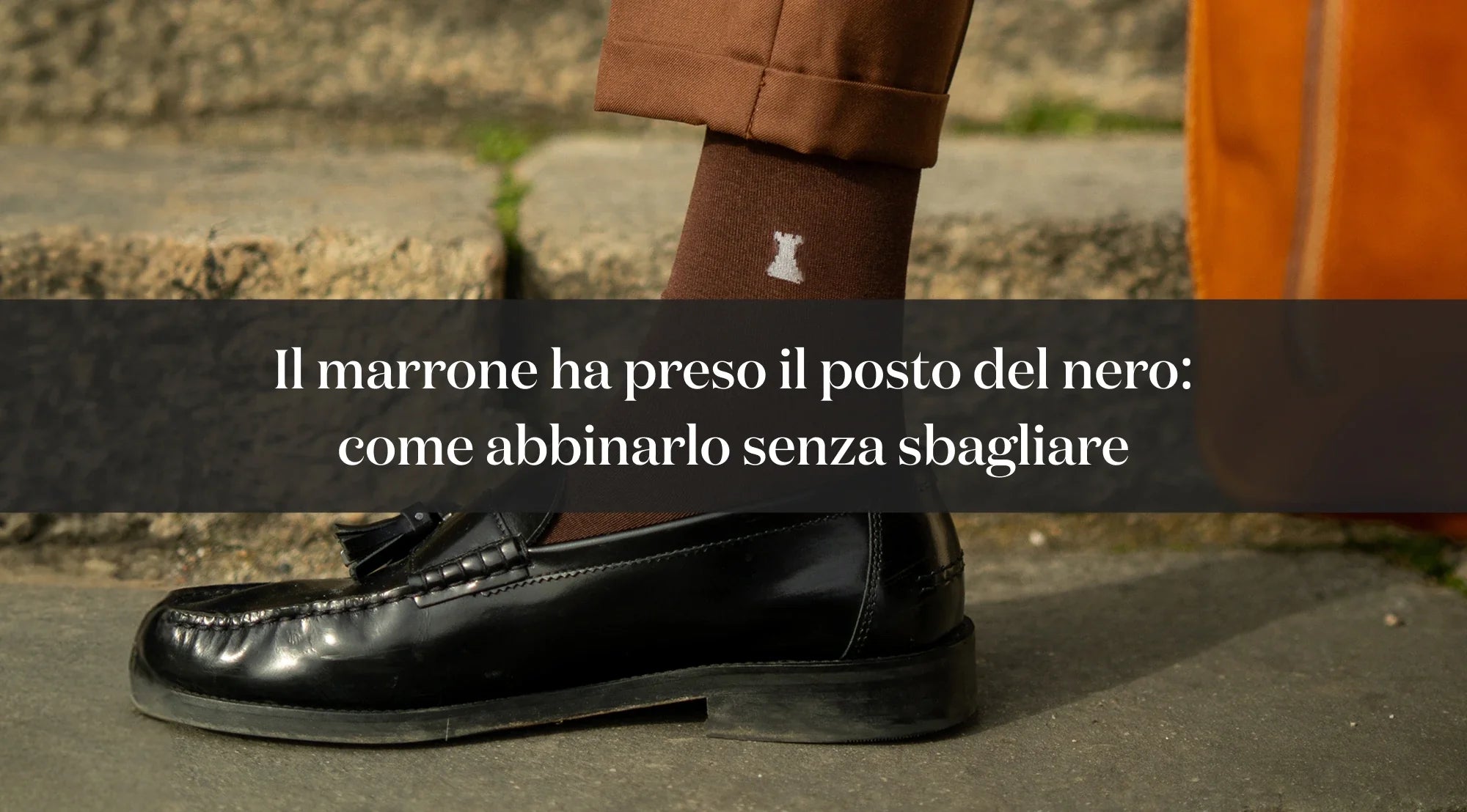 Dettaglio di mocassino nero con nappine, calza marrone e pantaloni marroni, con testo su come abbinare il marrone al posto del nero.
