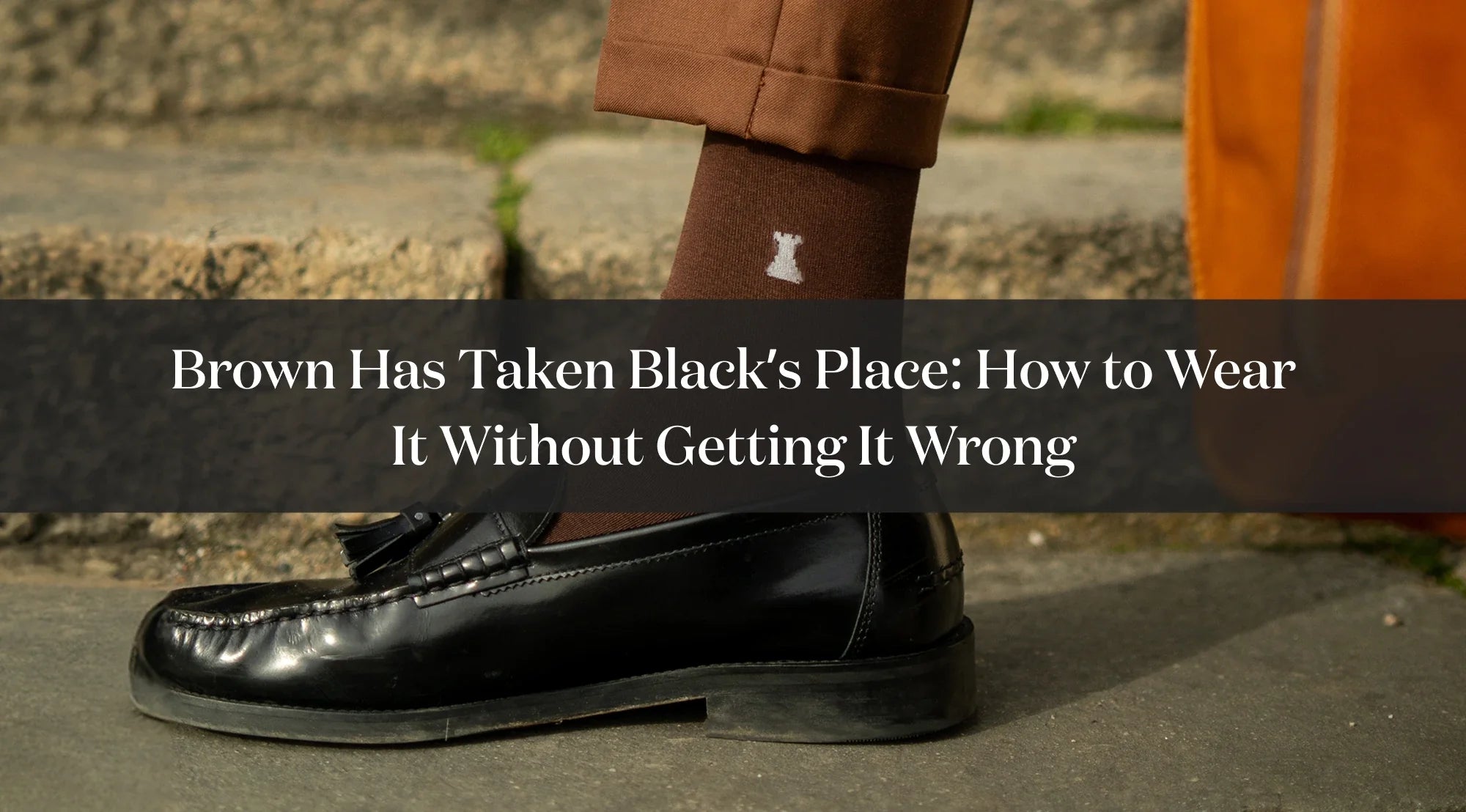Detail of a black tassel loafer, brown sock and brown trousers, with text about how to wear brown instead of black.
